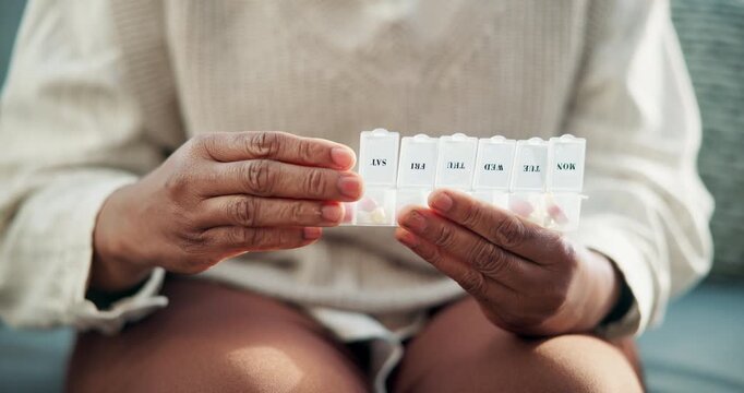 Woman, hands and pills with container on sofa for medication, prescription or daily dosage in home. Female person, patient or sorting tablets for weekly pharmaceuticals, medical plan or treatment