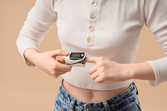Young woman checking her oxygen saturation and pulse rate with a finger pulse oximeter for health monitoring, this medical device is essential for health monitoring