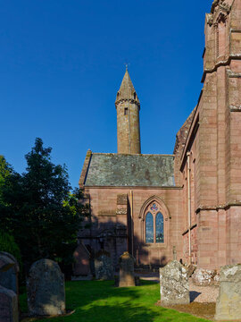 The Round Tower and South Transept of Brechin Cathedral set against a clear blue sky on an early morning in August.