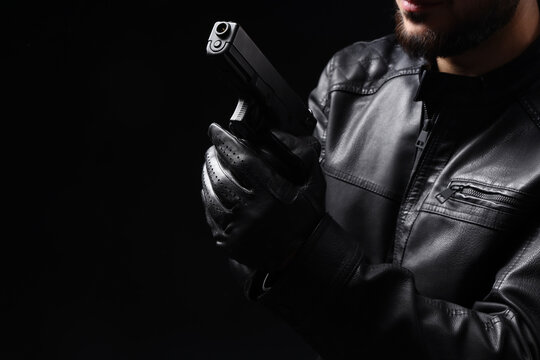 Man with gun on black background, closeup