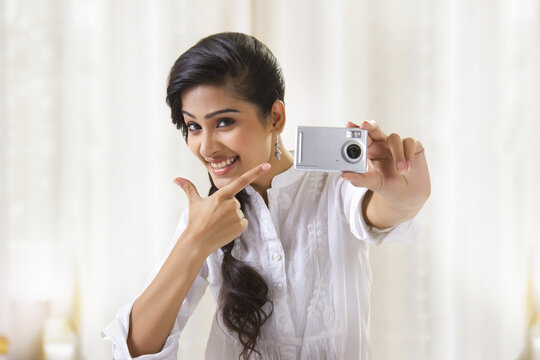 Young woman taking photograph with camera showing smiley face