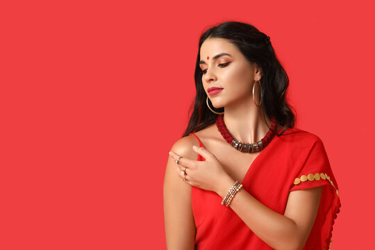 Beautiful young Indian woman in traditional sari on red background. Divaly celebration