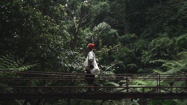 Woman walks across a bridge in a lush tropical jungle