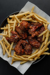 Top view of fried chicken wings and french fries on parchment paper © Cavan