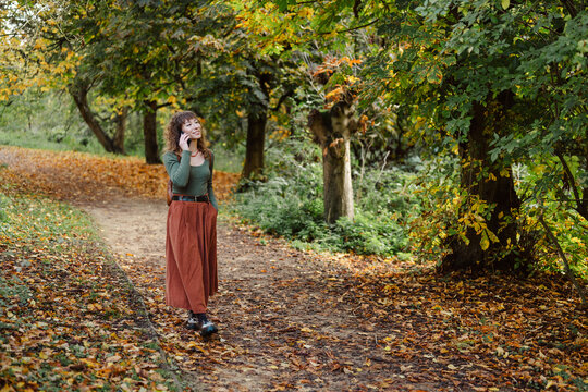 Woman talking on phone while walking in autumn park