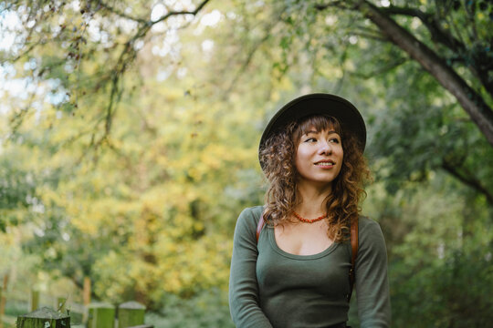 Young woman wearing hat enjoys a peaceful forest walk