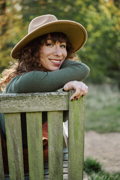 Smiling woman in a hat relaxing on a park bench
