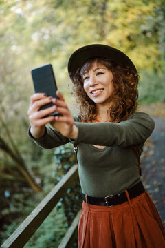 Smiling woman in a hat takes a selfie in nature
