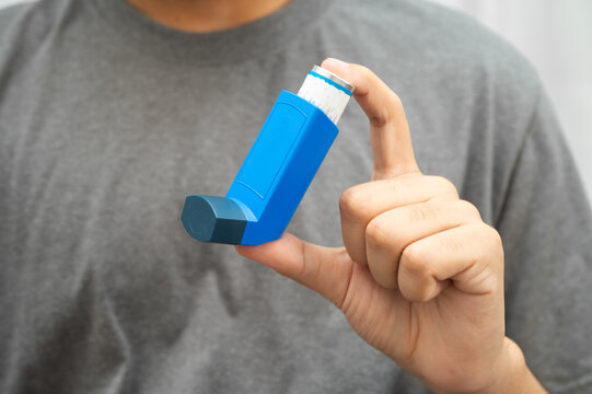 Asthma and chronic obstructive pulmonary disease COPD, Asian young man using metered dose inhaler MDI.