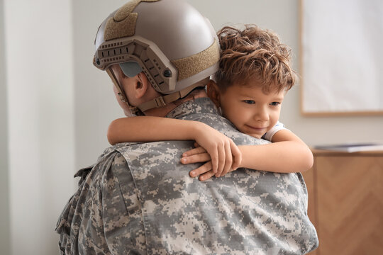 Little boy hugging his military father at home, closeup
