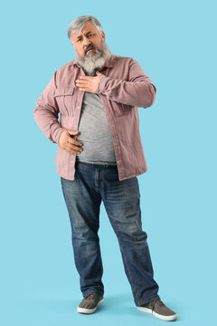 Portrait of sad senior man holding heart on blue background