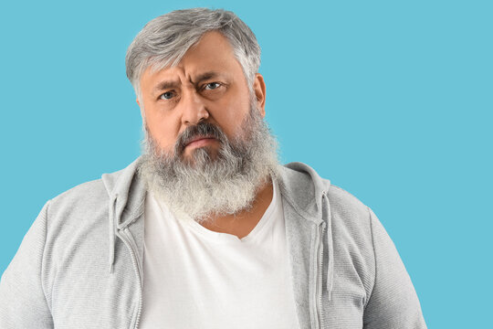 Portrait of sad senior man on blue background