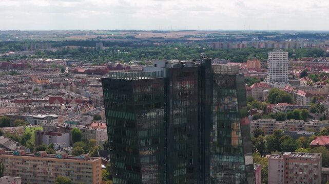A wide aerial shot zooming out from the modern Hanza Tower skyscraper to reveal the urban landscape, residential blocks, and greenery of Szczecin, Poland.