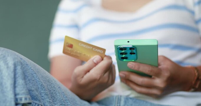Woman holding a smartphone and credit card for online shopping and digital payment via e-commerce app. Concept of fintech, cashless transaction, secure online purchase and mobile banking, close-up