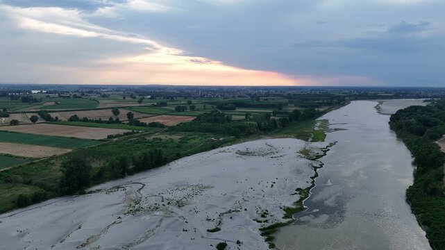 Po River near Isola Serafini, Monticelli d'Ongina, Piacenza, Emilia-Romagna, Italy, forms the border with Lombardy as exposed sandbars and the active channel reveal low water, drone lateral slide.