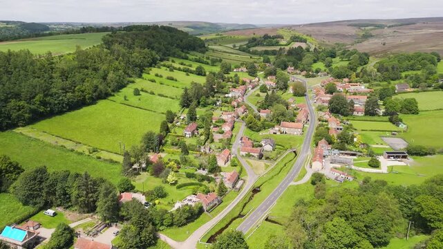 Aerial drone view flying over the picturesque village of Hutton-le-Hole in the North York Moors on a bright, sunny day