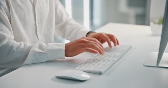 Person typing on keyboard at desk with computer and mouse