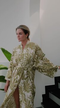 Elegant woman wearing luxury kimono robe in modern tropical home.