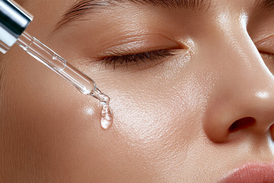 Close up of facial serum being applied with dropper to glowing healthy skin, luxury skincare routine featuring hydrating beauty treatment and cosmetic wellness concept