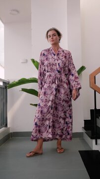 Elegant woman wearing luxury kimono robe in modern tropical home.