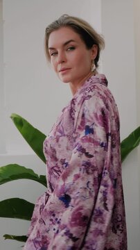 Elegant woman wearing luxury kimono robe in modern tropical home.