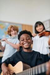 Obraz premium Happy smiling boy playing acoustic guitar in elementary school music class background for education poster and kids program banner