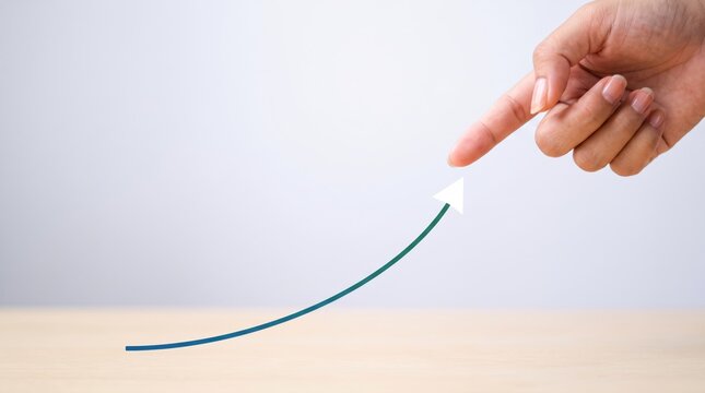 Hand pointing finger at rising green arrow curve graph symbolizing business growth, financial success, positive trend, and economic development on clean background.