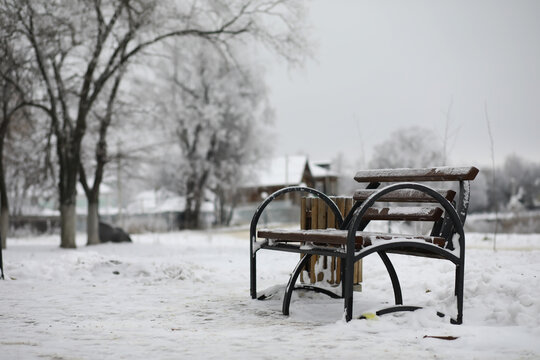 park bench on a winter alley at snowfall. bench with snow after snowstorm or in snow calamity in europe