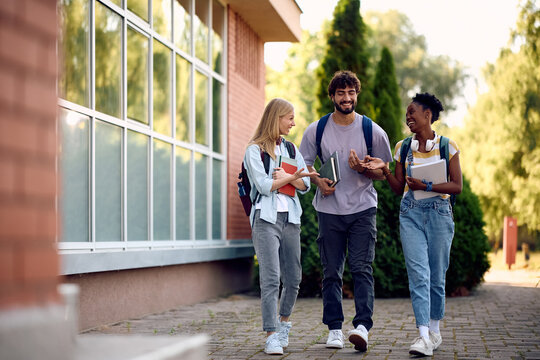 Happy diverse students talking while going on lecture at university.