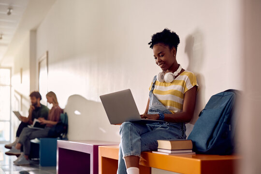 Black female student using laptop at university.