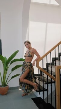 Woman models coordinated patterned resort wear with halter bikini top and flowing wide leg pants 