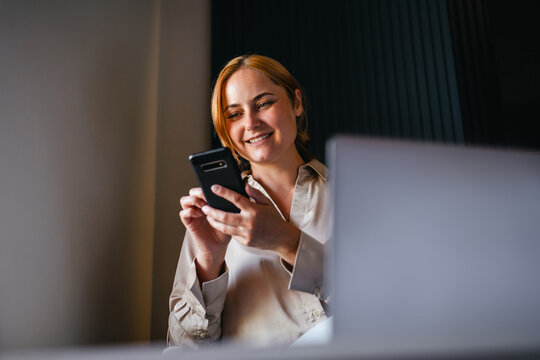 Happy young woman smiling at her smartphone