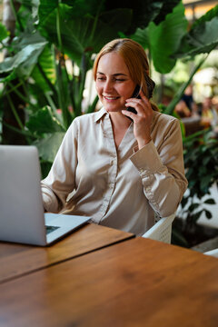 Happy woman working on laptop and taking a call