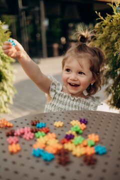 Laughing toddler showing colorful sensory toy outdoors