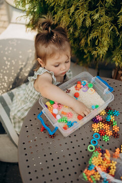 Toddler practicing sensory exploration with rice bin outdoors