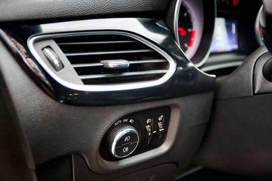 Dashboard headlight switch control panel with air vent in modern car interior showing automatic light modes and adjustments for fog illumination, headlamps, illumination level.