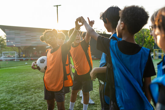 Two teams of kid football players touching hands before soccer match. 