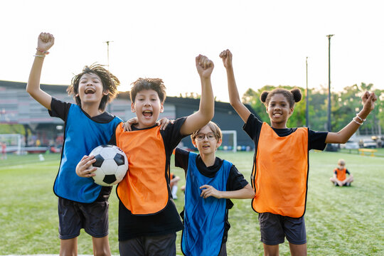 Portrait of diverse kid football players celebrating victory together.