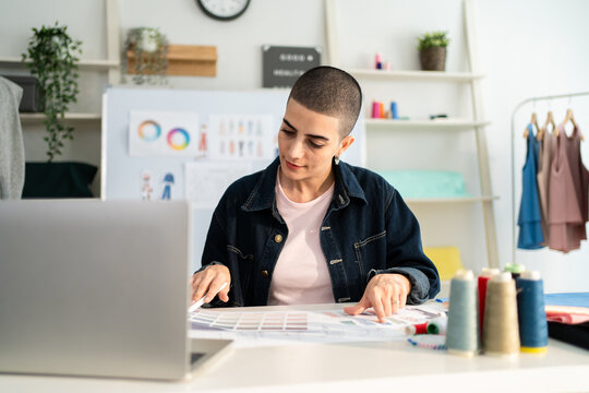 Caucasian young woman working as fashion designer in tailor studio. 