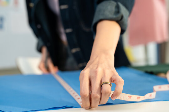 Close up of young woman working as fashion designer in tailor studio. 
