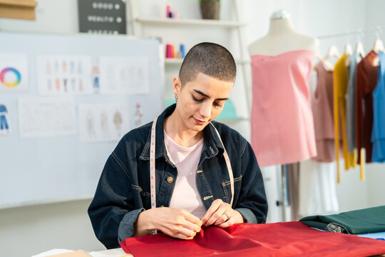 Caucasian young woman working as fashion designer in tailor studio. 