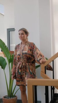 Elegant woman wearing luxury kimono robe in modern tropical home.