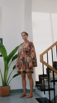 Elegant woman wearing luxury kimono robe in modern tropical home.