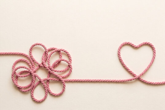 Self love and healing concept, a tangled pink cord unravelling into a clean heart shape, with copy space