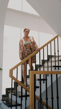 Elegant woman wearing luxury kimono robe over  swimsuit in modern tropical villa.
