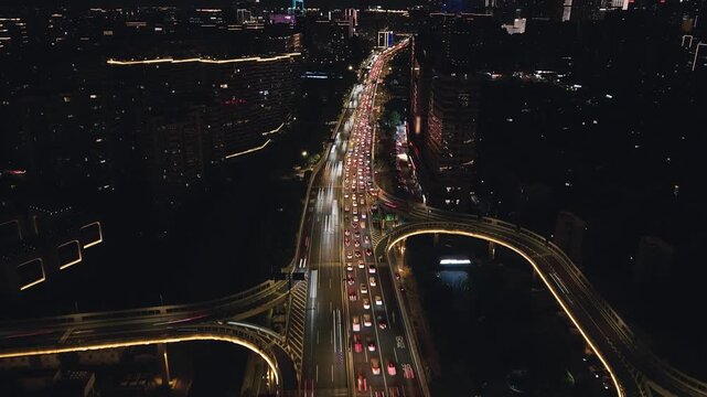 Aerial view captures a busy Hangzhou highway interchange at night with glowing lights and towering apartments
