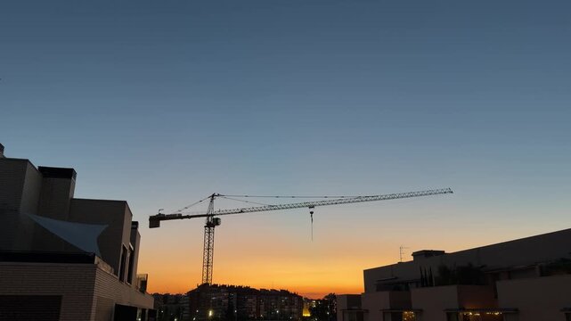 Construction crane silhouette against a colorful sunset sky