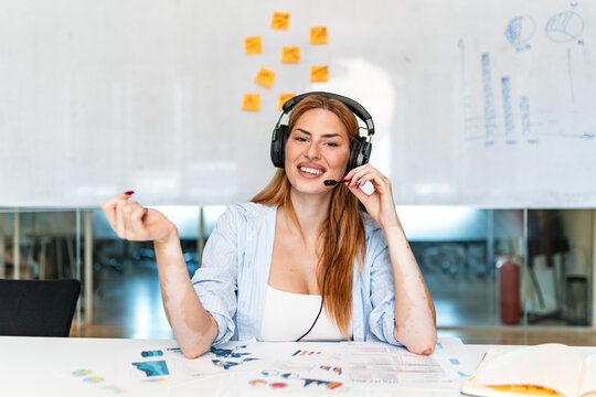 Customer support representative working. Call center operator with headset, Smiling woman at office desk with documents. Professional helpline agent talking with client.