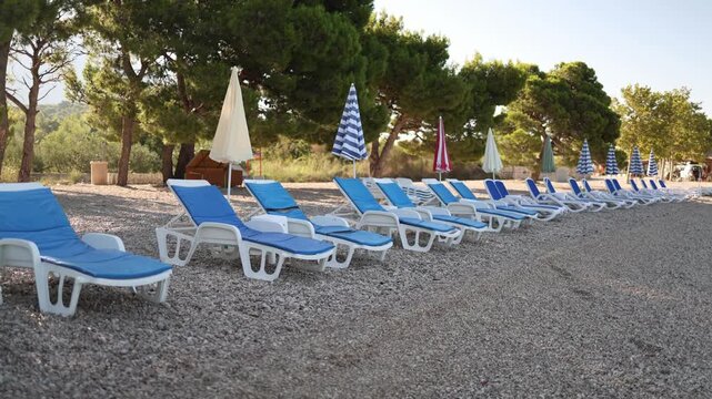 Rows of sun loungers and closed umbrellas are arranged on a silent pebble beach as a seaside resort prepares beach facilities for the upcoming summer tourist season ahead