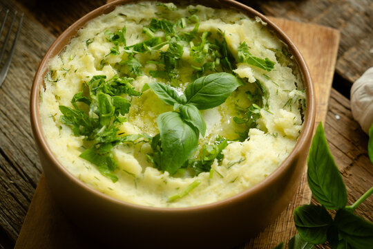 Dish of creamy mashed potatoes topped with a sprinkle of fresh herbs. Thanksgiving meal.